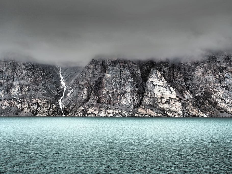 gray cliff beside body of water covered by fog, gray mountain cliff near body of water HD wallpaper