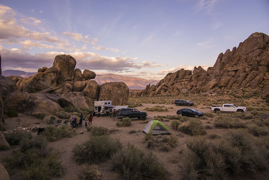 vehicle surrounded by mountain, cars beside rock formations, desert