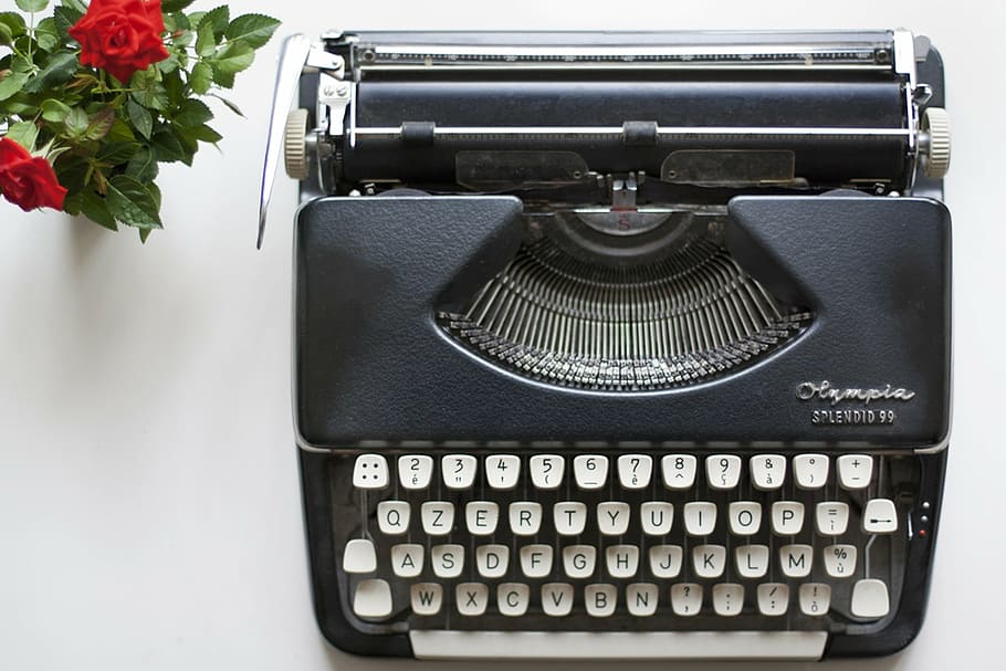 aerial view photography of black typewriter beside red roses HD wallpaper