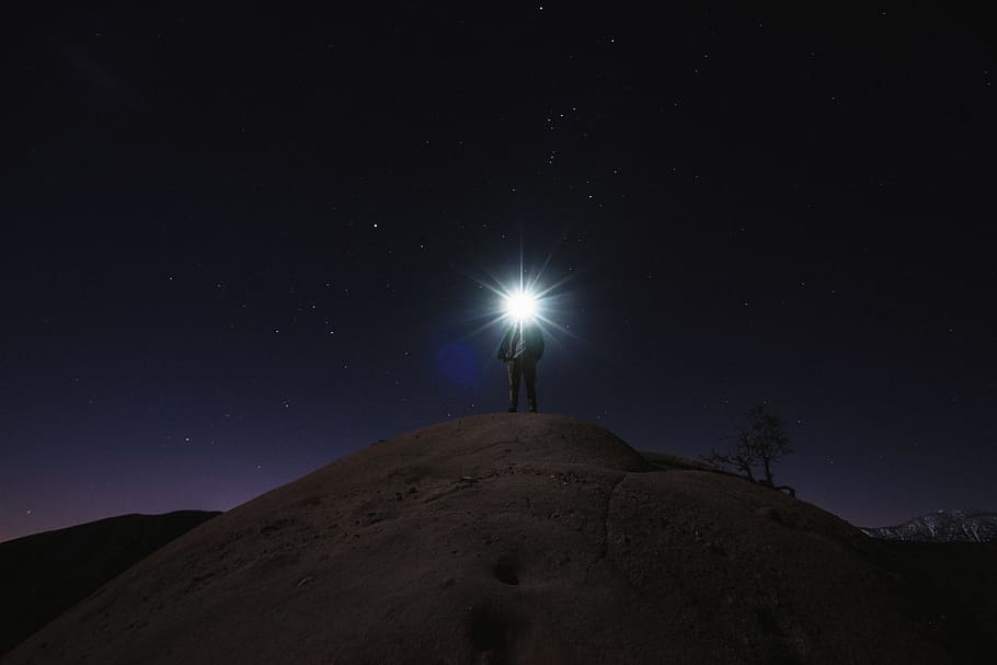 man standing on mountain white holding flashlight, person standing on hill during nighttime HD wallpaper