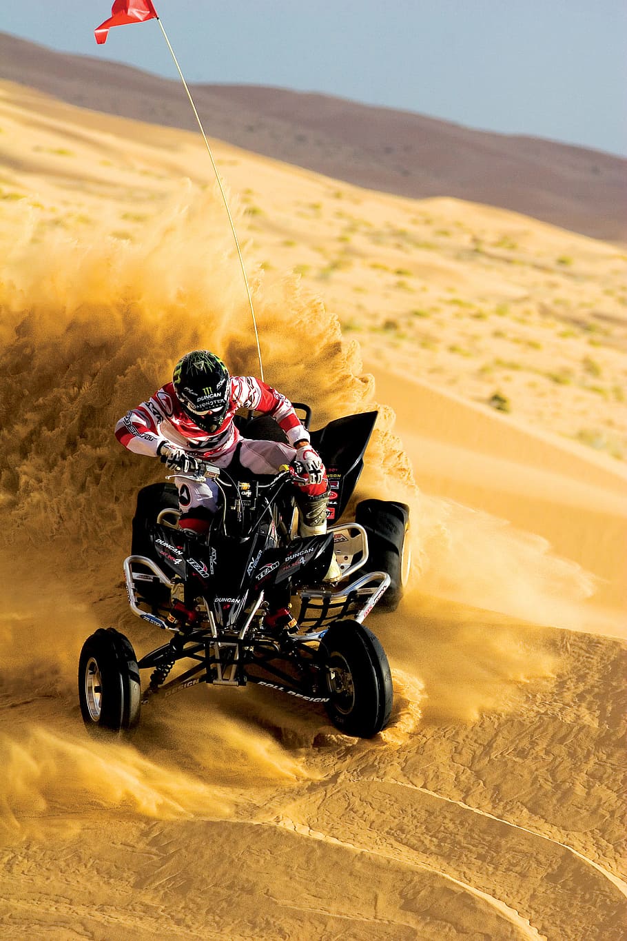 person riding on ATV and drift on sand, man riding on black ATV on desert sands