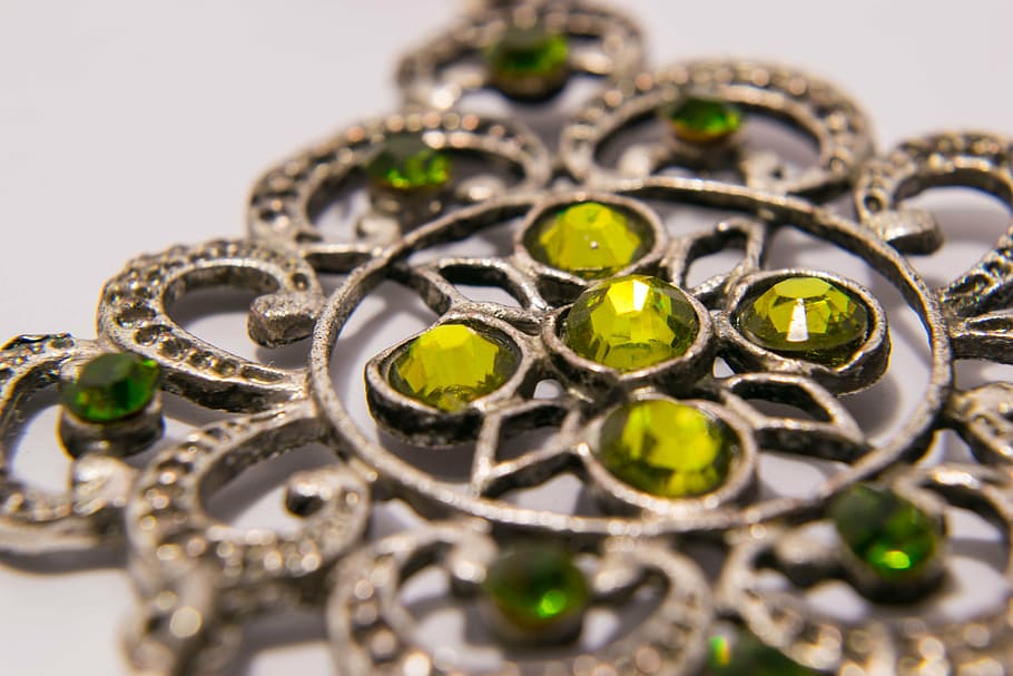 green gemstone encrusted silver-colored accessory on white surface HD wallpaper