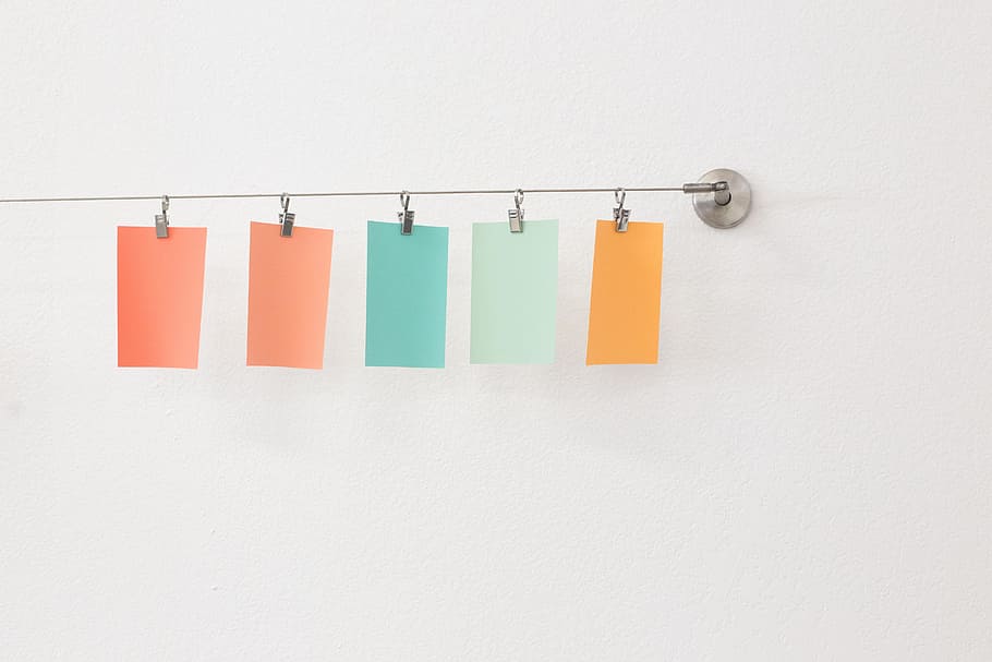 five assorted-color sticky notes hanged on gray wall hooks HD wallpaper