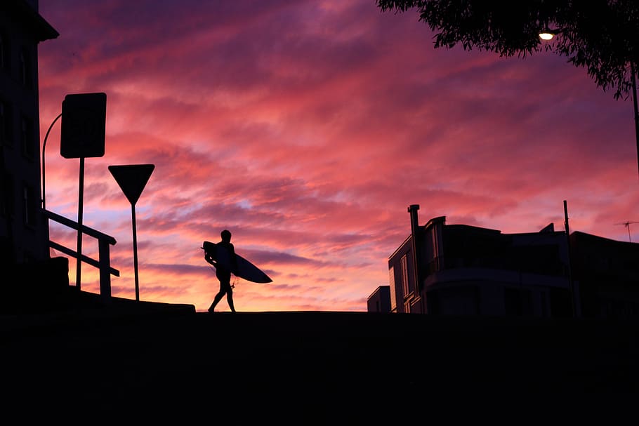 silhouette photography of man walking with a surfboard, silhouette person's holding surfboard under cloudy sky HD wallpaper