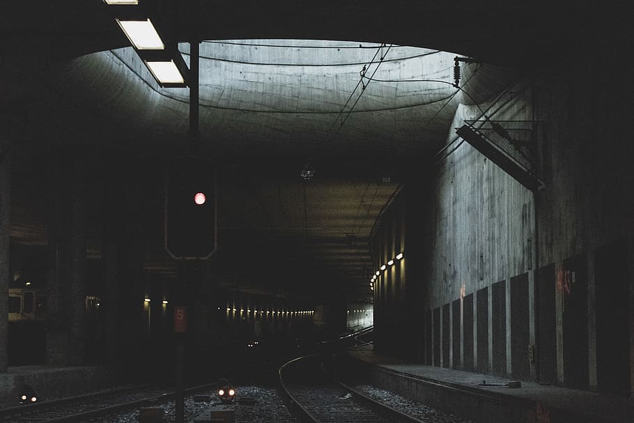gray metal train rail at daytime, dark concrete subway, urban