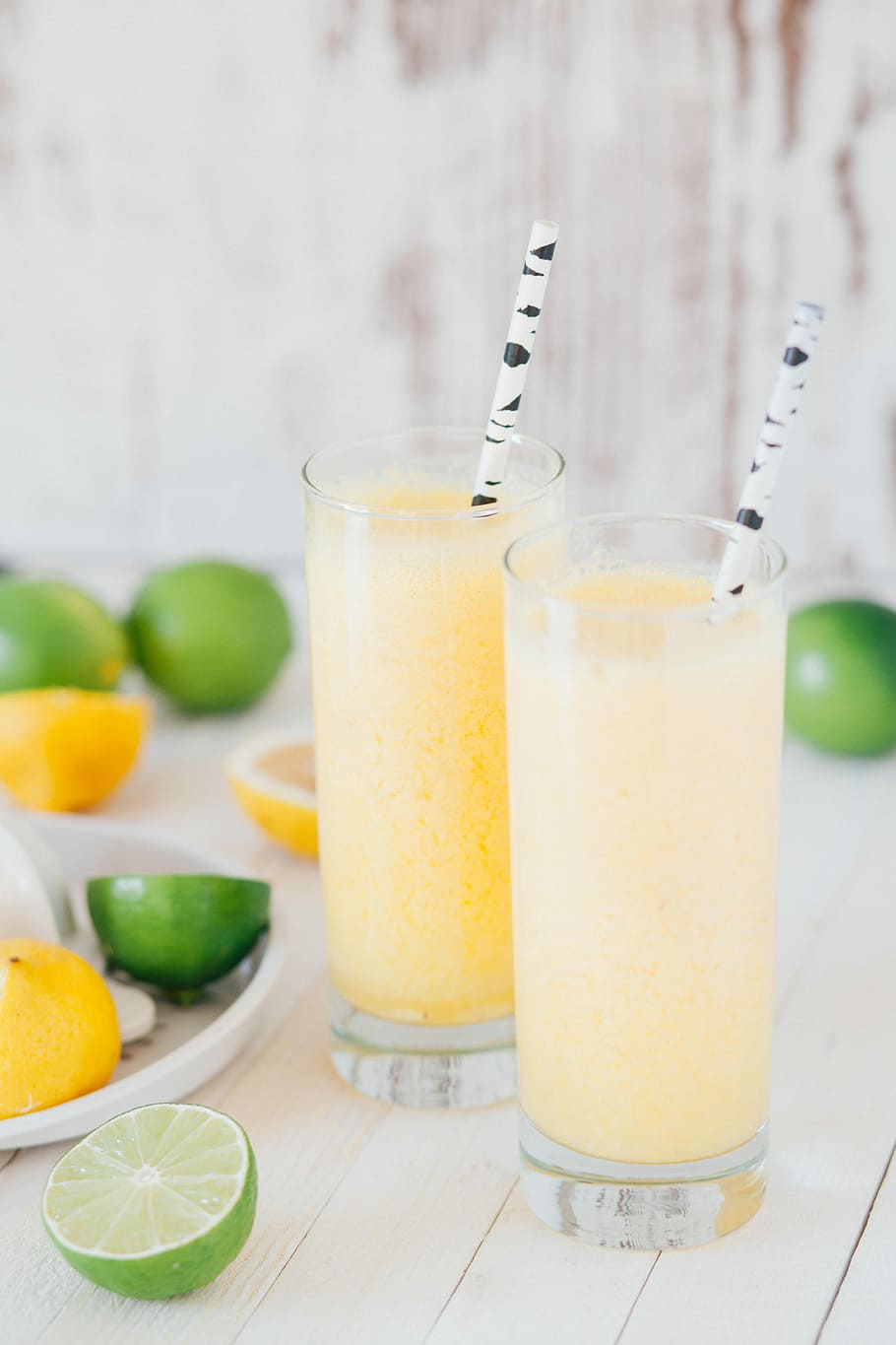 two clear glass cups, two glasses filled with shakes beside slide lemons on top of table, HD wallpaper