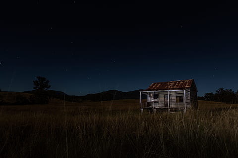 gray and brown wooden house surrounded by grass near mountain, brown and black wooden house surrounded by green grass at night HD wallpaper