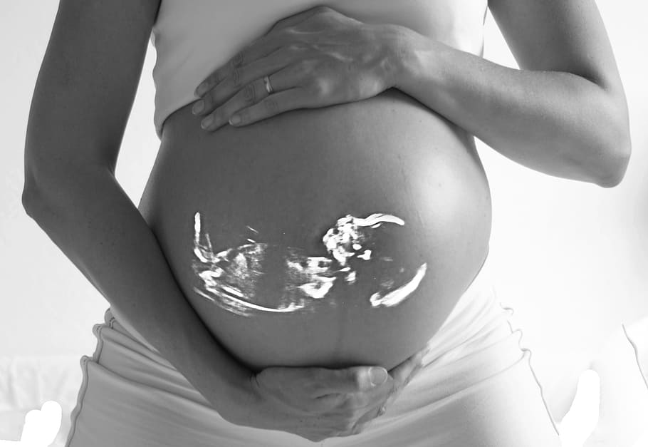grayscale photo of woman holding her belly with baby, pregnant