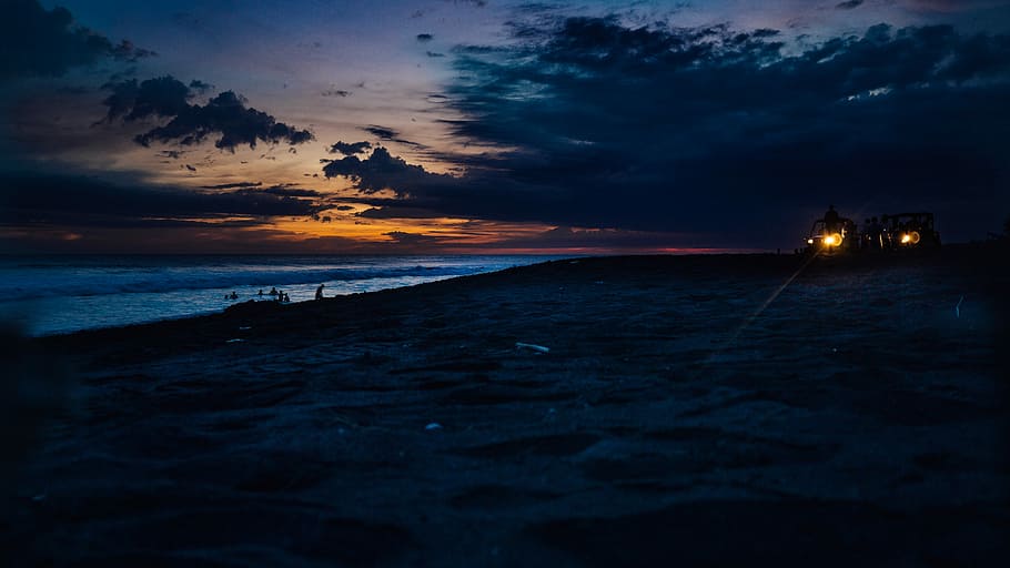 silhouette of person riding on car at the beach during dusk, body of water under orange sunset HD wallpaper