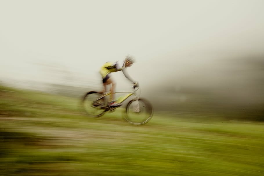 man riding yellow bicycle on green grass, mountain bike, downhill