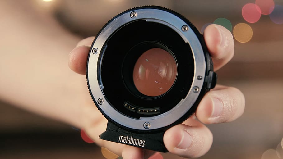 selective focus photography of gray Metabones camera, person holding black and silver Metabones camera lens