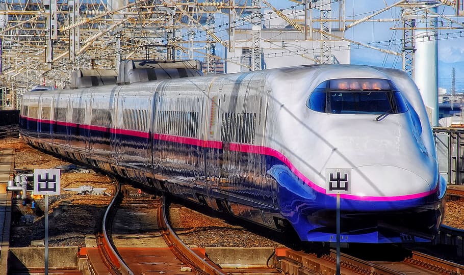 white and blue bullet train on brown trail rails during daytime