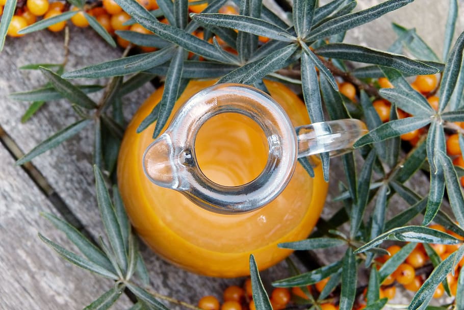 clear glass pitcher near small round fruit, sea buckthorn, juice