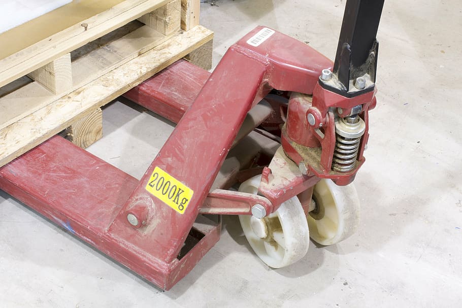 closeup photo of brown wooden pallet on red pallet truck, industrial