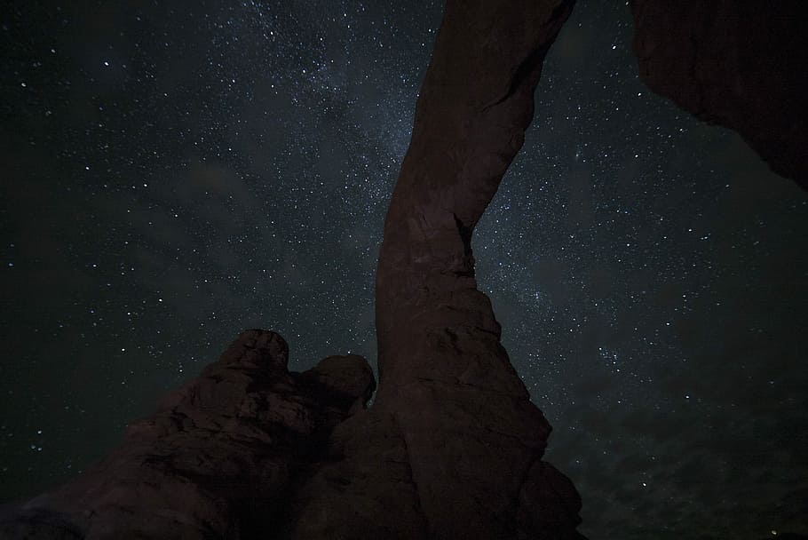 milky way behind rock formation, photo of brown rock formation under white stars at nighttime HD wallpaper