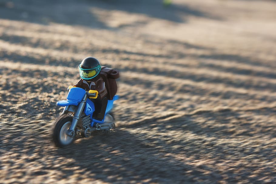 selective focus photography of minifig riding blue motorcycle