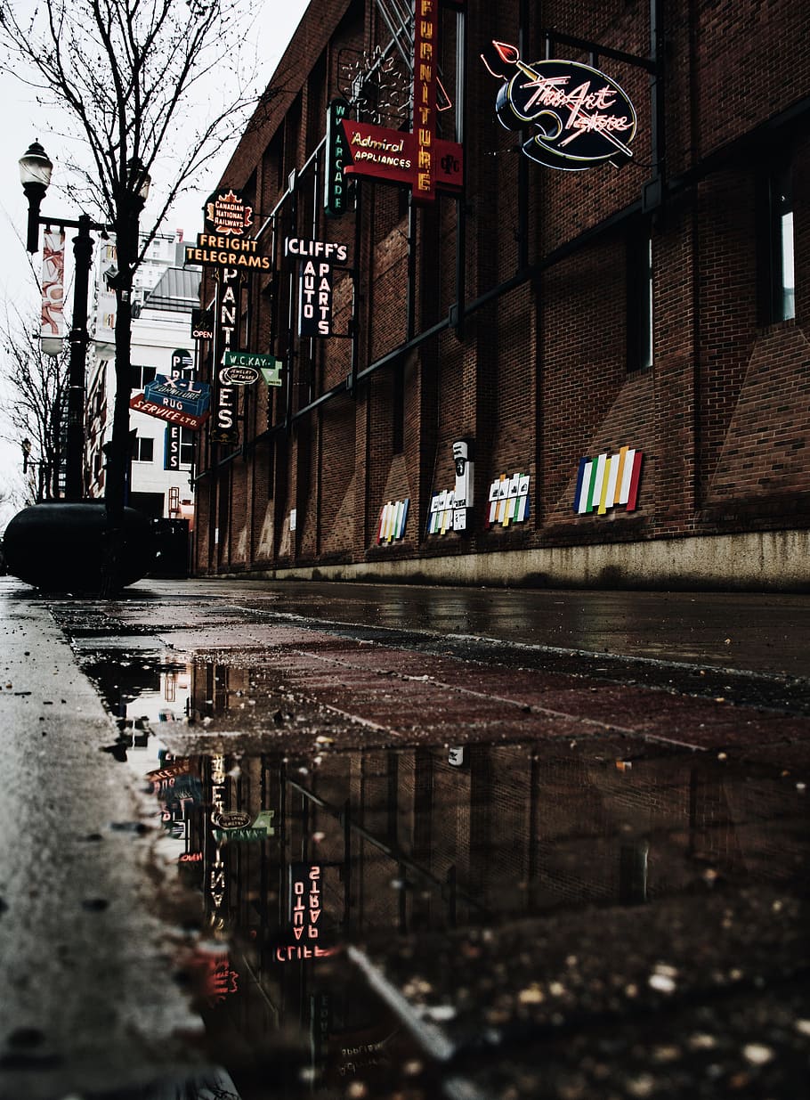 brown brick building with signages, low-angle photography of empty road between store facades HD wallpaper