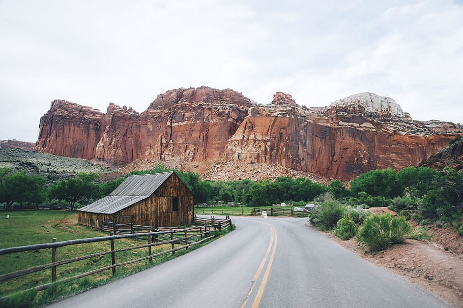 winding road near butte, brown house near gray roadway, empty HD wallpaper