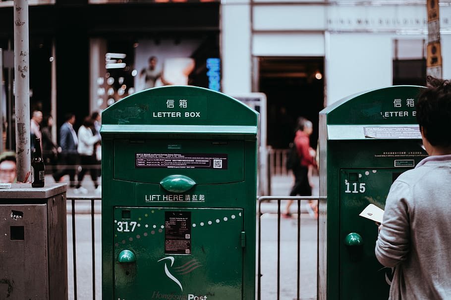 man standing in front of post, person standing in front of letter box carrying paper HD wallpaper
