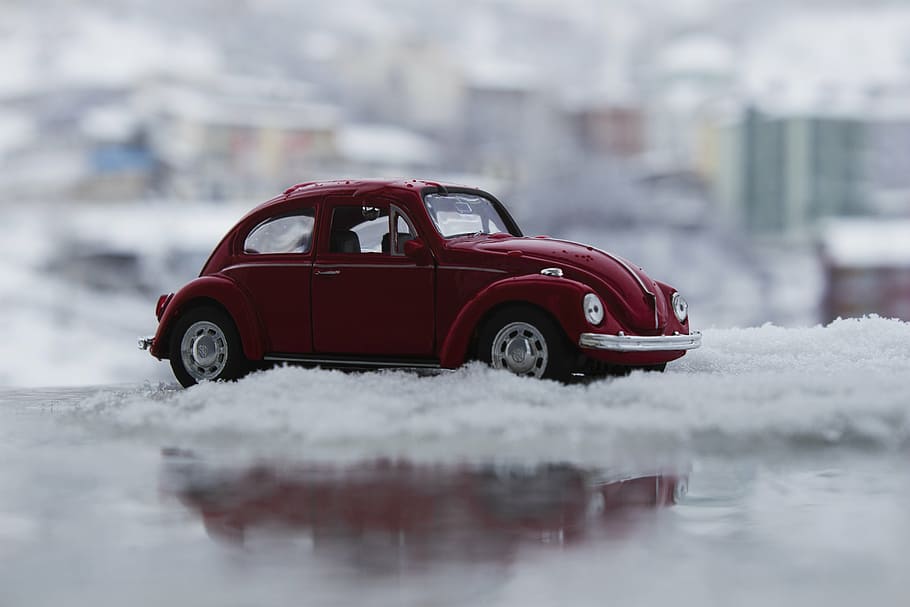 selective focus photography of red Volkswagen Beetle coupe scale model