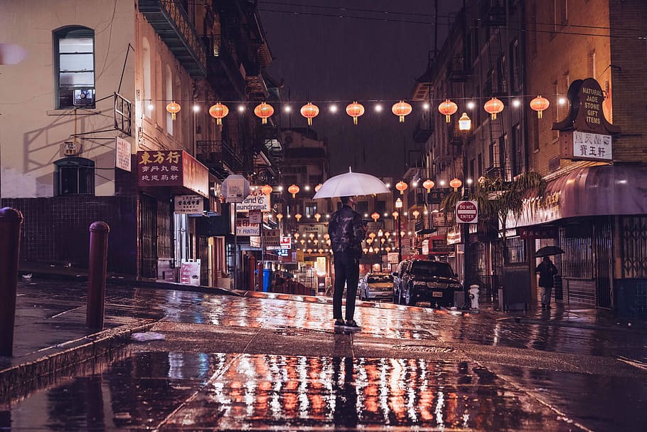 person standing on street holding umbrella during night time, man under white umbrella in the middle of the street during nighttime