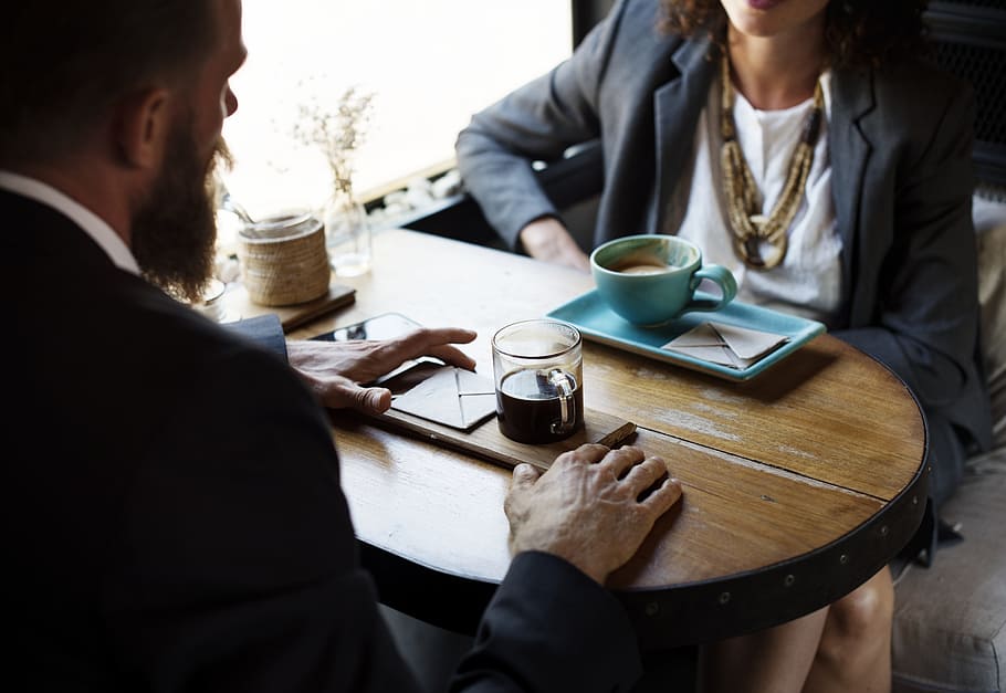 man and woman talking by the table with cup of coffees, discussion