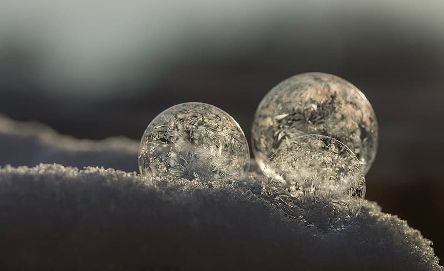three round ornaments on snow closeup photo, soap bubbles, cold