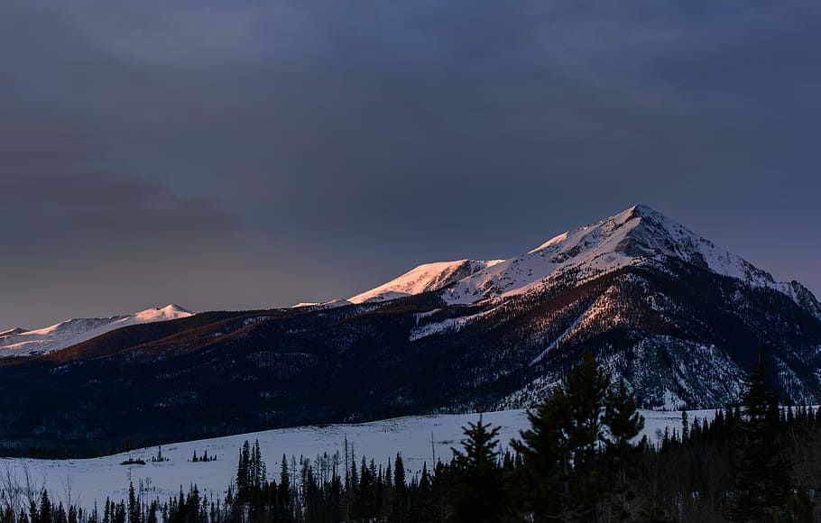 snowy mountain under cloudy sky, brown mountain near trees, grey HD wallpaper