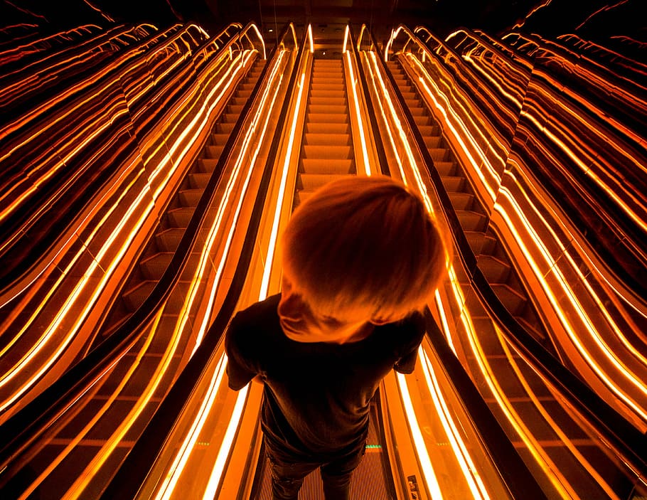 man on escalator with light, person on black crew-neck T-shirt standing on scalator HD wallpaper
