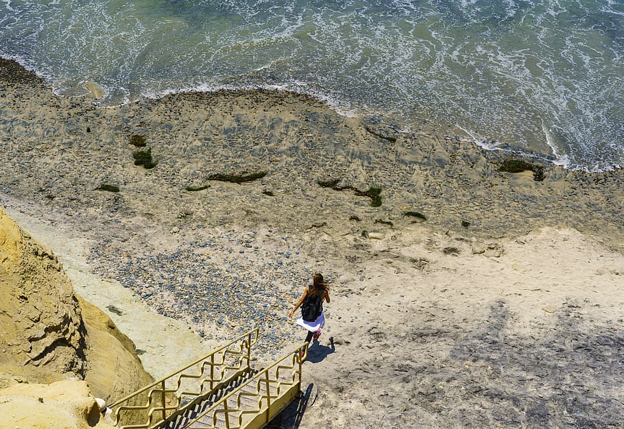 woman running towards body of water, ocean, beach, rock, stair