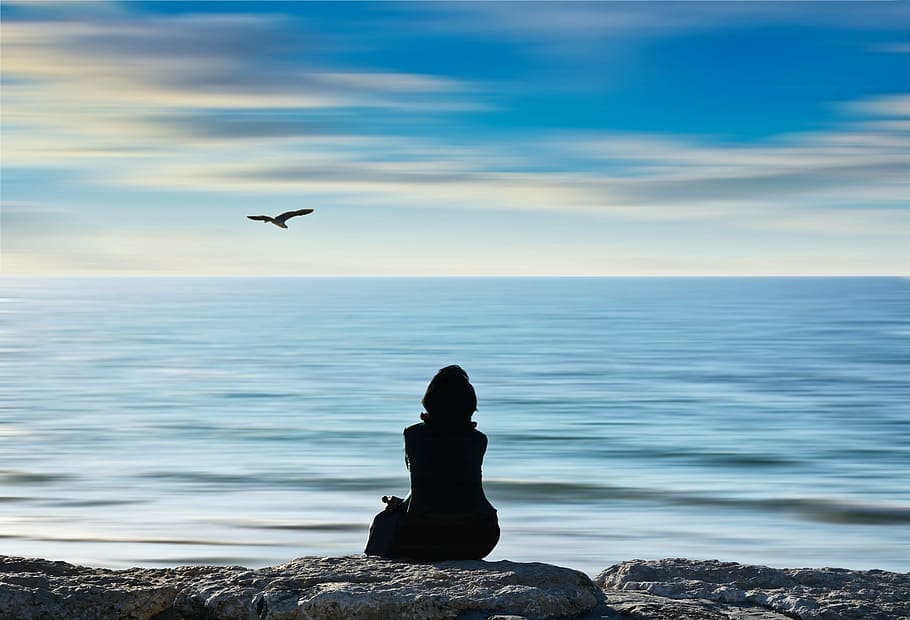 silhouette photograph of person sitting on rock near sea, beach HD wallpaper