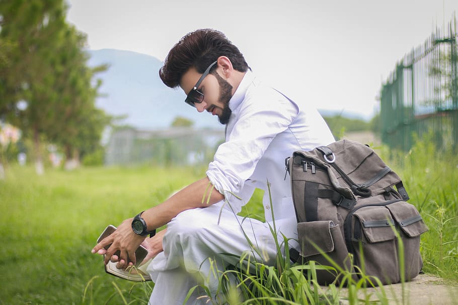 man sitting beside his backpack while looking down, Fashion, Style