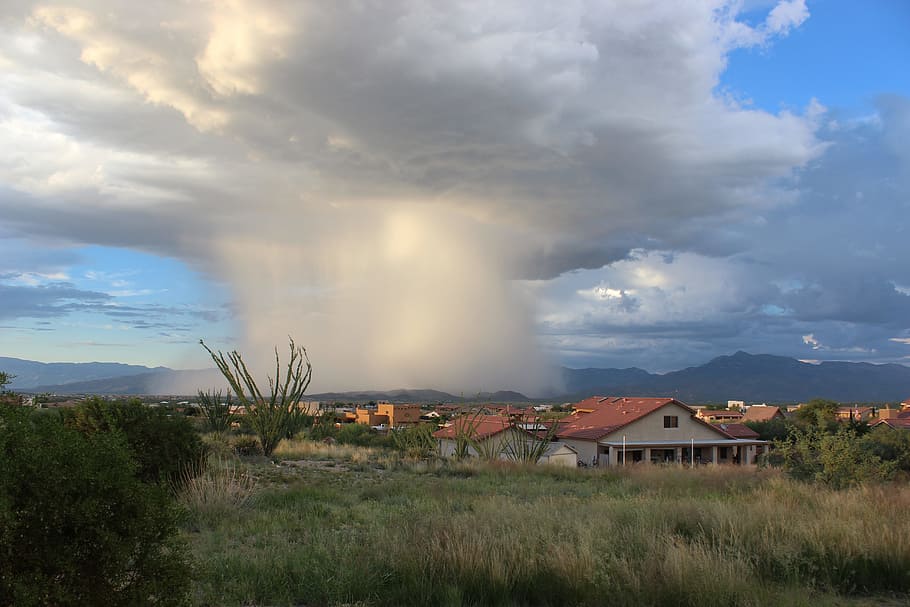 photo of cloud formation near houses during daytime, houses near forest below white clouds HD wallpaper