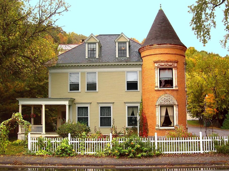 photo of brown and beige 3-story house between trees, new england