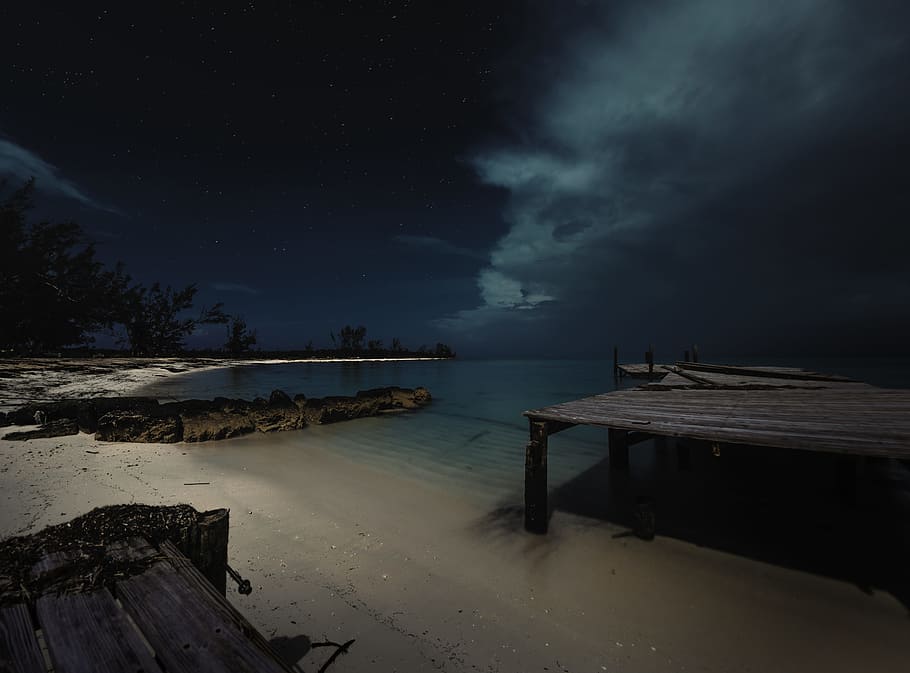 brown wooden dock and body of water under black sky during nighttime, ocean near sand and dock during night time, HD wallpaper