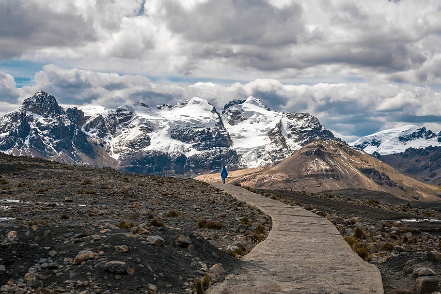 person walking toward snow-capped mountain, view of person walking on mountains path