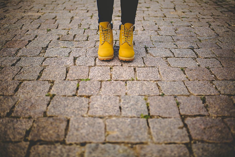 person wearing brown work boots, woman standing on gray brick flooring HD wallpaper