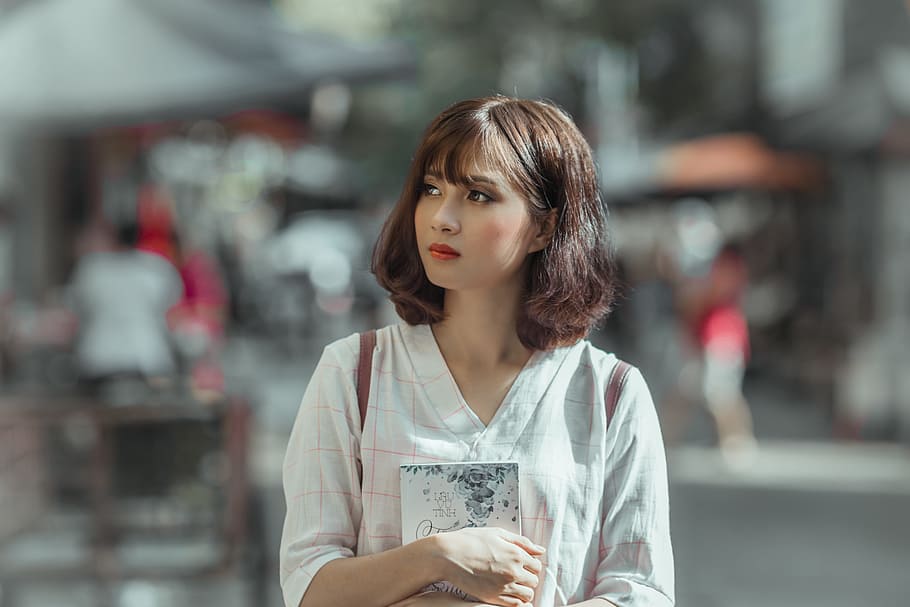 selective focus photography of woman holding book, vietnam women