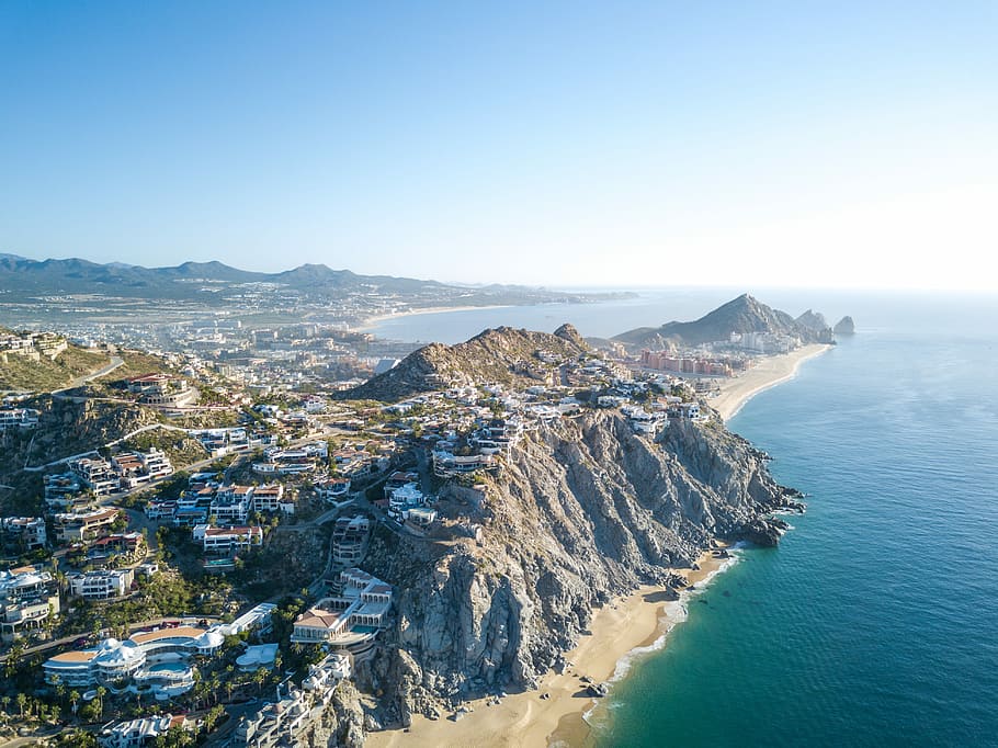 aerial photography of mountain with village near sea, buildings and houses near body of water HD wallpaper