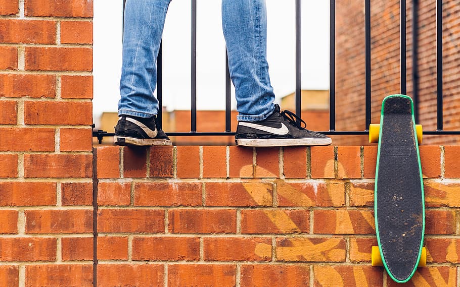 person wear black Nike sneakers standing on concrete brick wall HD wallpaper