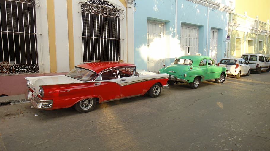 two red and green sedan park beside blue and gray painted buildings HD wallpaper