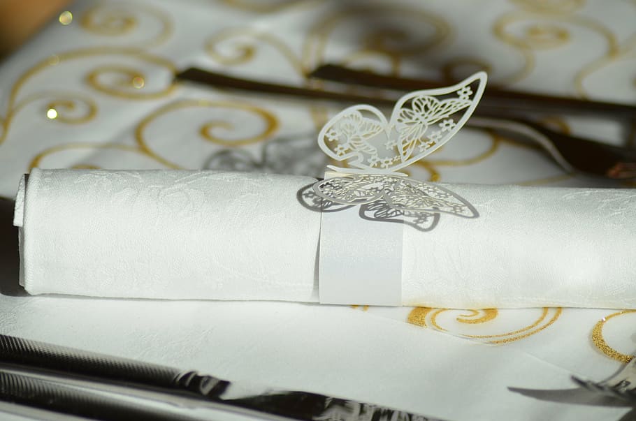 white rolled invitation card on table, napkin ring, napkin paper ring