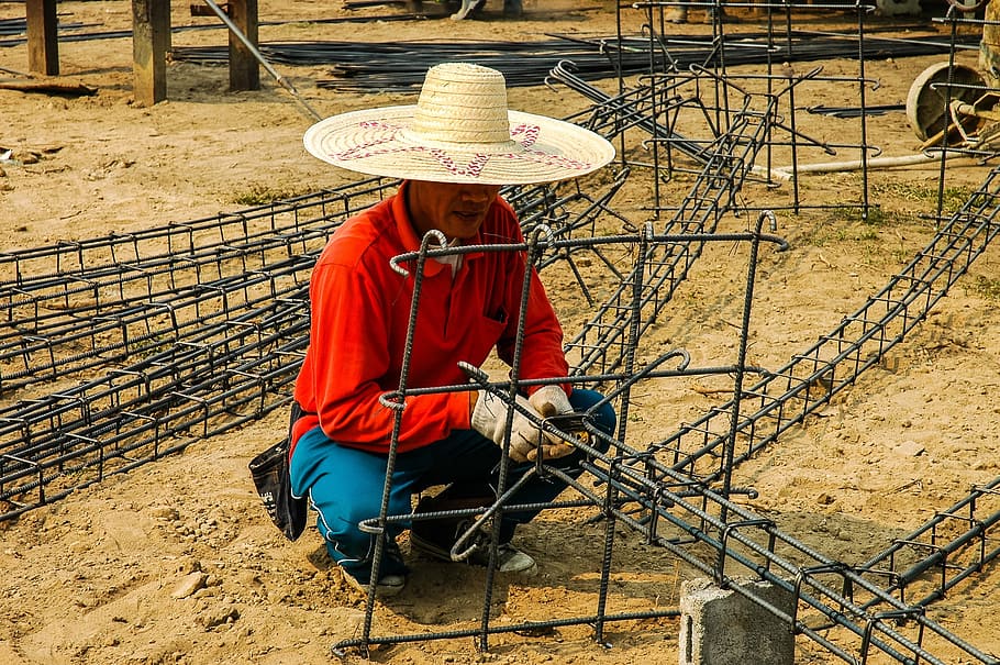 man squatting on ground while holding black metal frames during daytime HD wallpaper