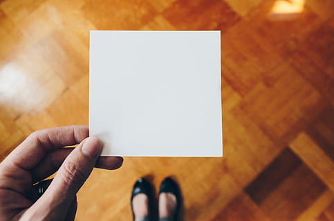 person holding white paper over brown wooden floor, person white card HD wallpaper
