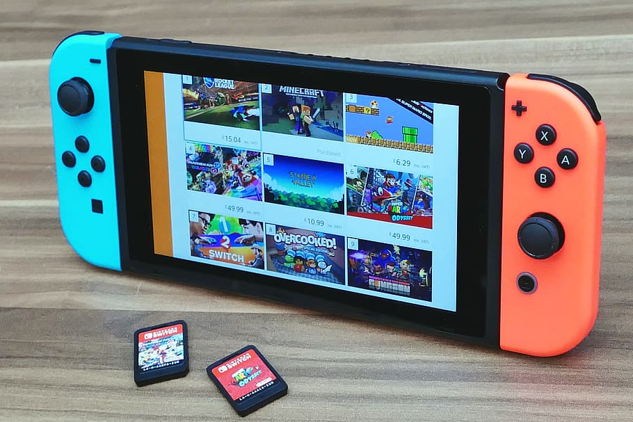 Nintendo Switch turned on on brown surface near two game cartridges, HD wallpaper