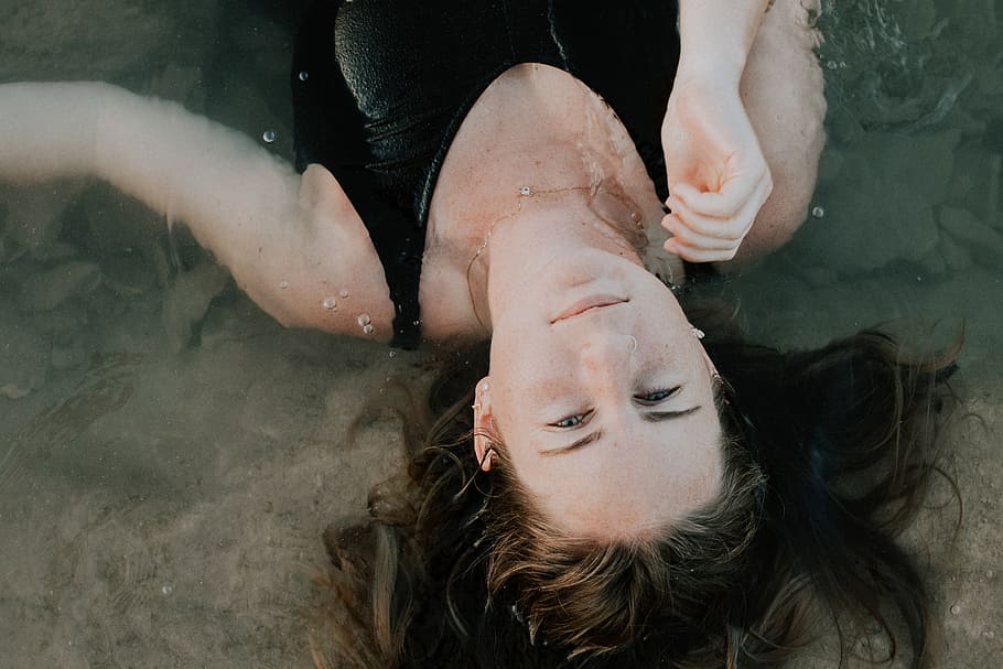 woman in black tank top, woman in tank top lying on body of water