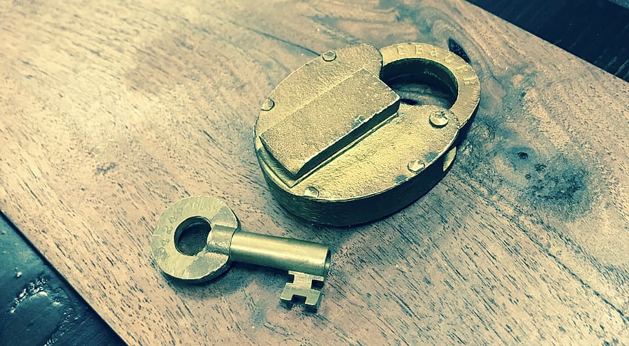 gray padlock beside key on brown wooden board, unlock, symbol HD wallpaper