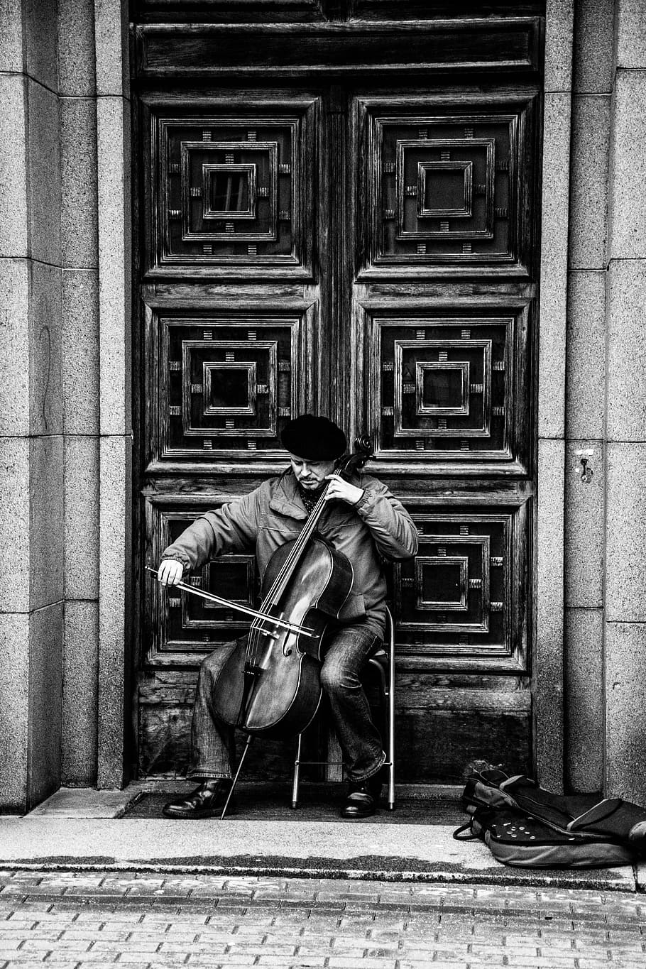 illustration of person playing cello, man playing double bass in front of large door