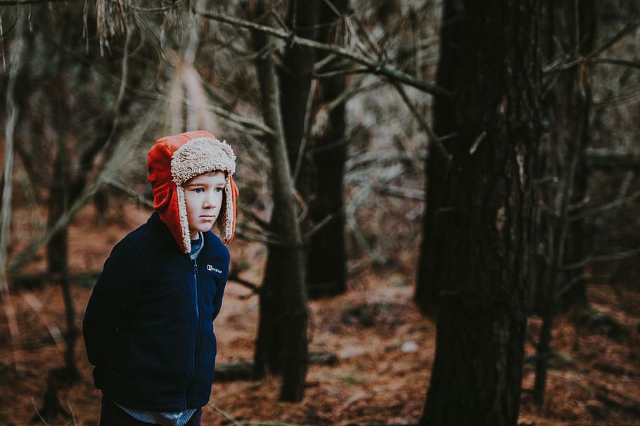 Boy in the woods, boy with black jacket and red hat waling in the middle of forest HD wallpaper