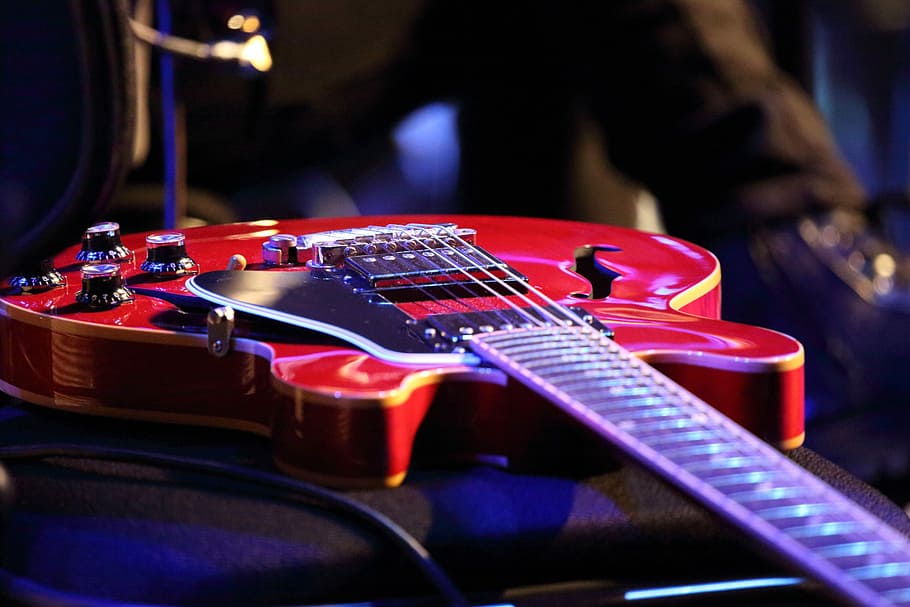 selective focus photography of red jazz guitar, etc, played, instrument